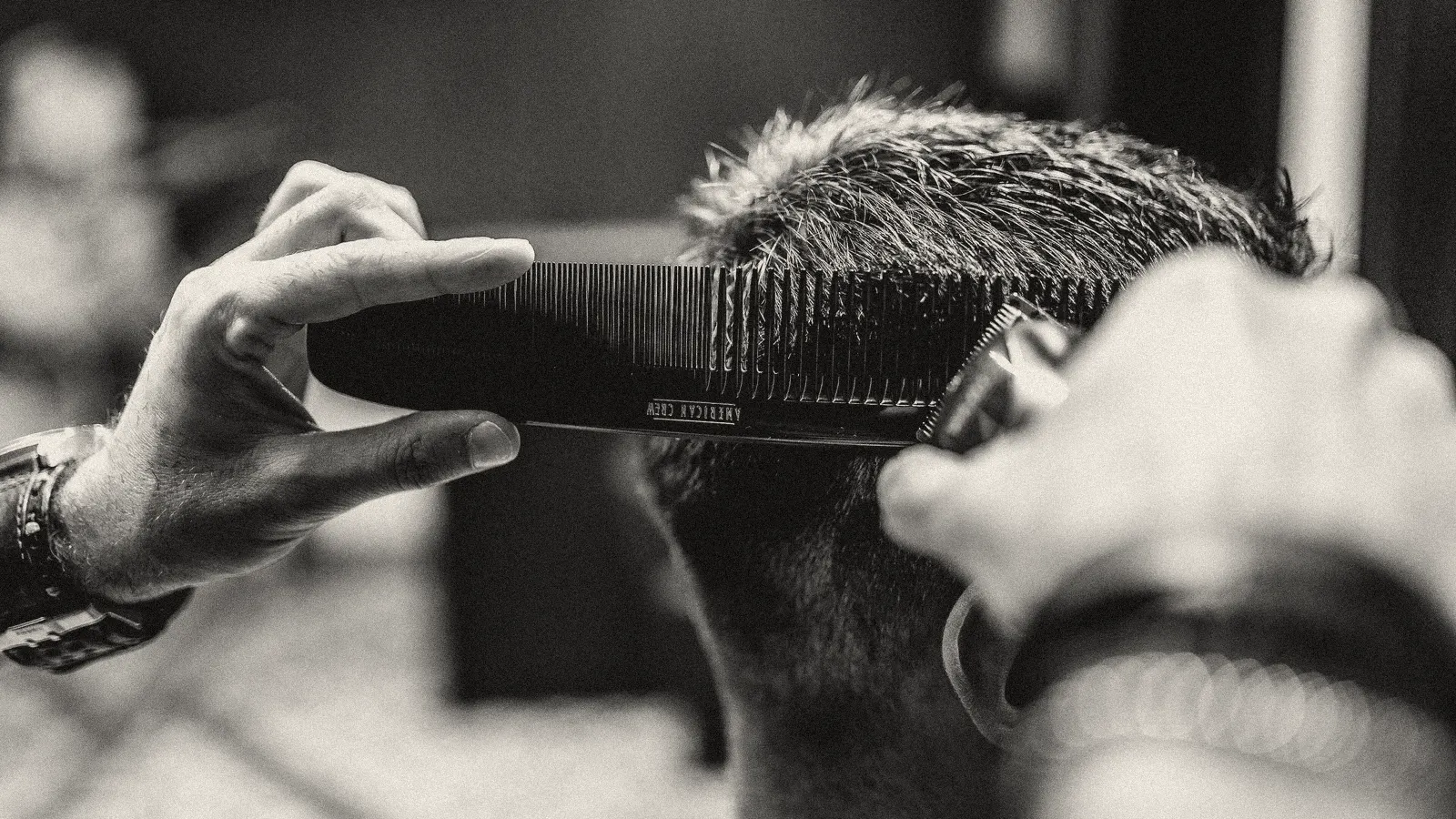 Barbero cortando el pelo con peineta y máquina, en blanco y negro (foto ilustrativa)