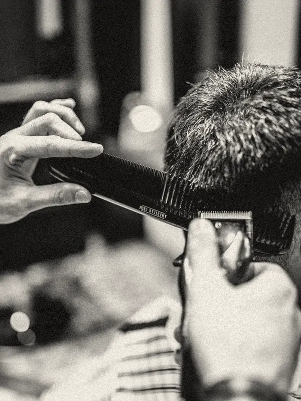 Barbero terminando un corte con peineta y máquina (foto ilustrativa)